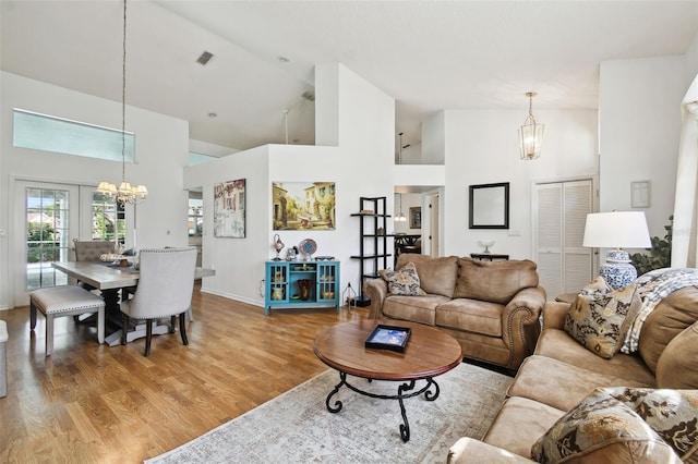 living room with french doors, hardwood / wood-style flooring, high vaulted ceiling, and a chandelier