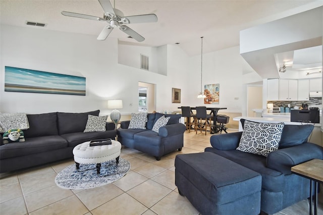 living room featuring ceiling fan, a towering ceiling, and light tile patterned floors