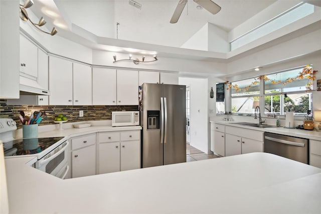 kitchen featuring a high ceiling, sink, white cabinetry, appliances with stainless steel finishes, and ceiling fan