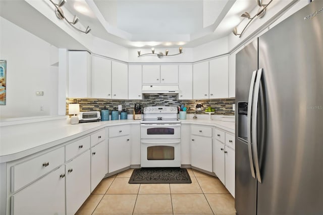 kitchen with white electric range oven, stainless steel fridge, premium range hood, and white cabinets