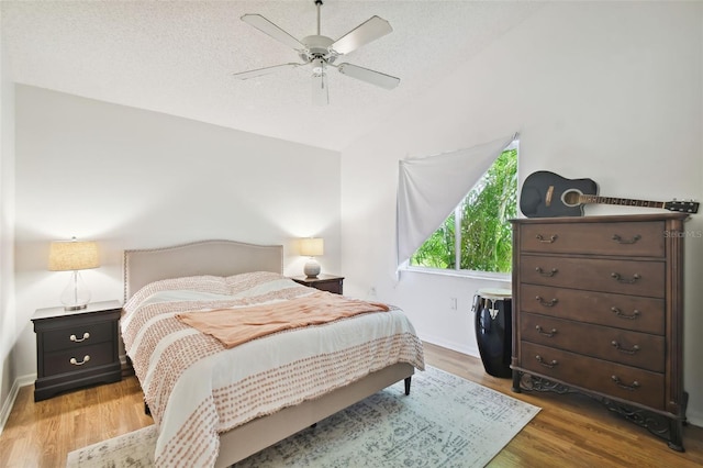 bedroom with dark wood-type flooring, vaulted ceiling, a textured ceiling, and ceiling fan