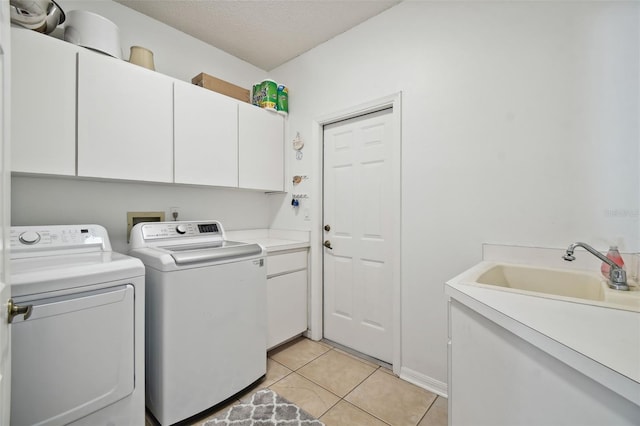 washroom with cabinets, a textured ceiling, independent washer and dryer, light tile patterned flooring, and sink