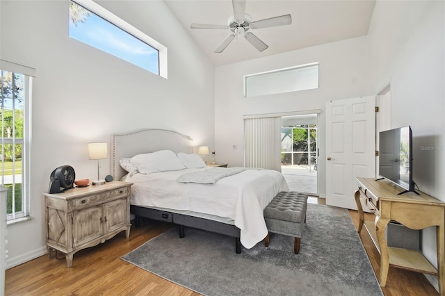 bedroom with ceiling fan, wood-type flooring, multiple windows, and access to exterior