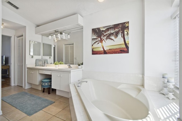 bathroom featuring lofted ceiling, tile patterned flooring, a relaxing tiled tub, vanity, and a textured ceiling