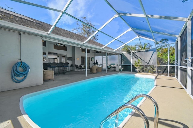 view of pool with a patio, glass enclosure, and ceiling fan