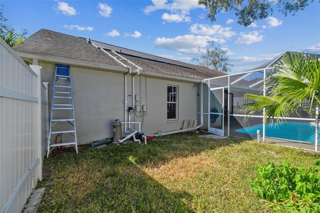 rear view of property with a lanai and a yard