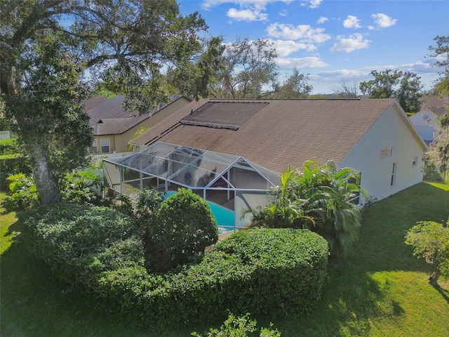 rear view of house featuring a yard and glass enclosure