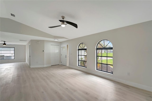 empty room with ceiling fan, plenty of natural light, light wood-type flooring, and vaulted ceiling