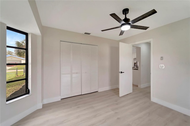 unfurnished bedroom featuring light hardwood / wood-style floors, ceiling fan, and a closet