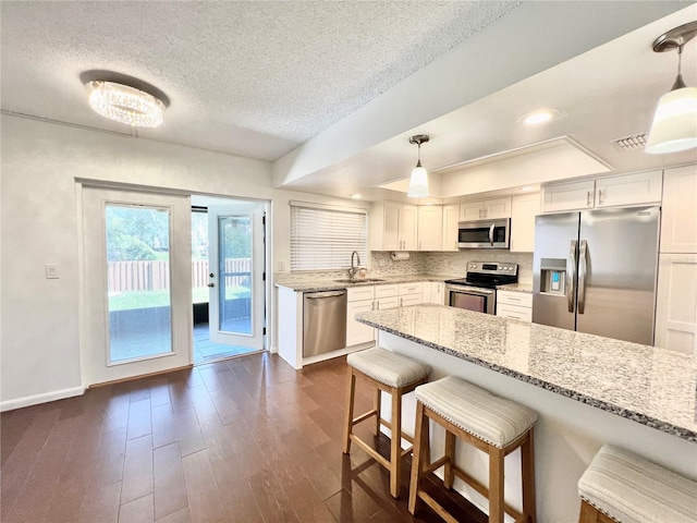 kitchen featuring white cabinets, stainless steel appliances, sink, and pendant lighting