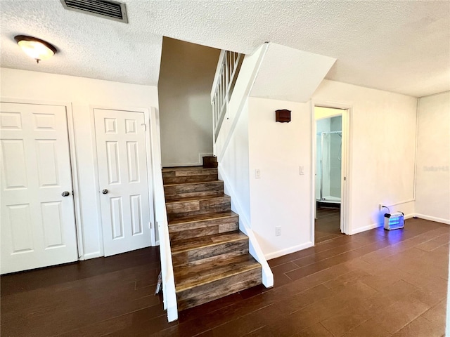 staircase with hardwood / wood-style floors and a textured ceiling