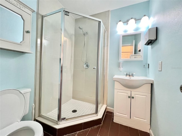 bathroom featuring vanity, tile patterned flooring, toilet, and an enclosed shower