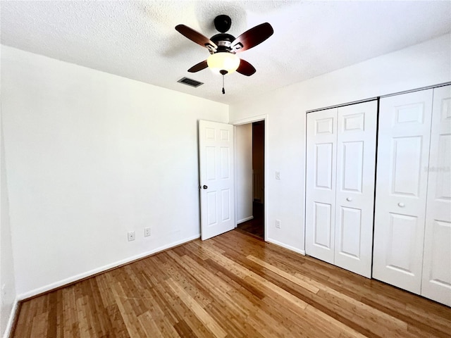 unfurnished bedroom with a closet, a textured ceiling, light wood-type flooring, and ceiling fan