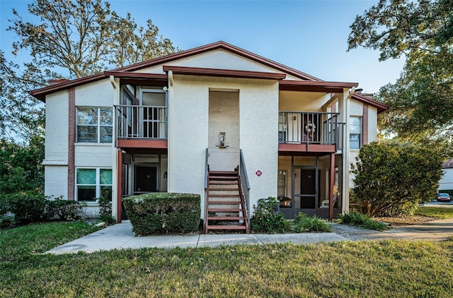 view of front of property featuring a balcony and a front lawn