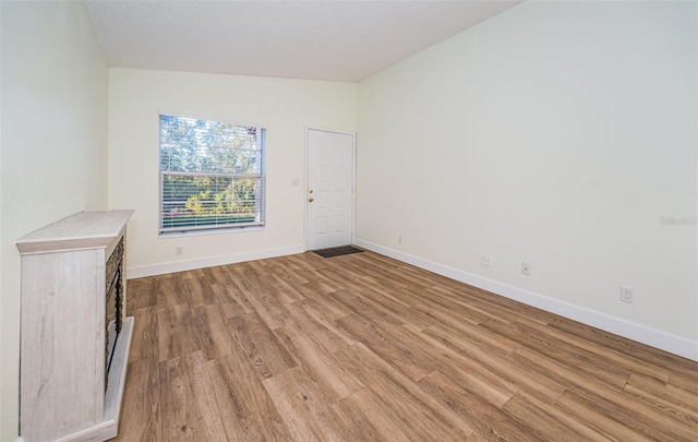 3455 Countryside Blvd Unit 52, Clearwater, FL 33761 - unfurnished living room featuring baseboards, vaulted ceiling, and light wood-style floors