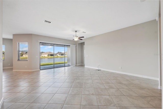 tiled spare room with a water view and ceiling fan