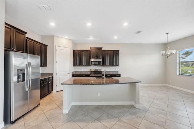 kitchen with stainless steel appliances, dark stone countertops, a center island with sink, sink, and dark brown cabinetry