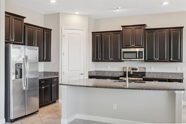 kitchen featuring light tile patterned flooring, stainless steel appliances, and an island with sink