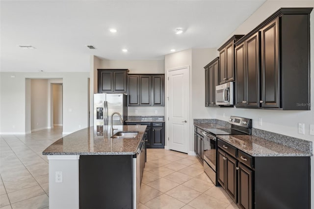 kitchen featuring sink, dark brown cabinets, stainless steel appliances, light tile patterned floors, and a kitchen island with sink