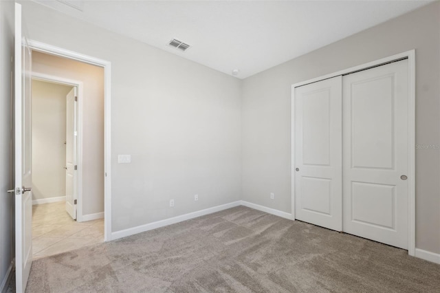 unfurnished bedroom featuring light carpet and a closet