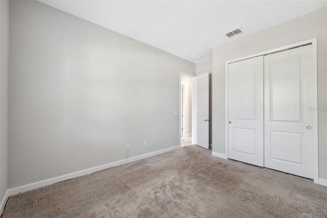 unfurnished bedroom featuring a closet and light colored carpet