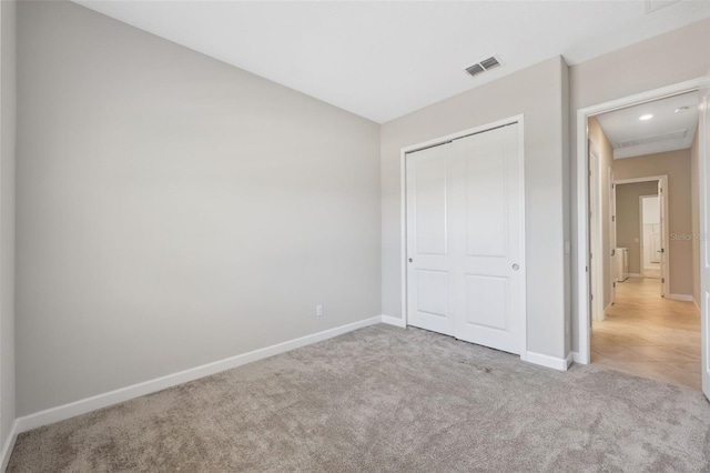 unfurnished bedroom featuring light carpet and a closet