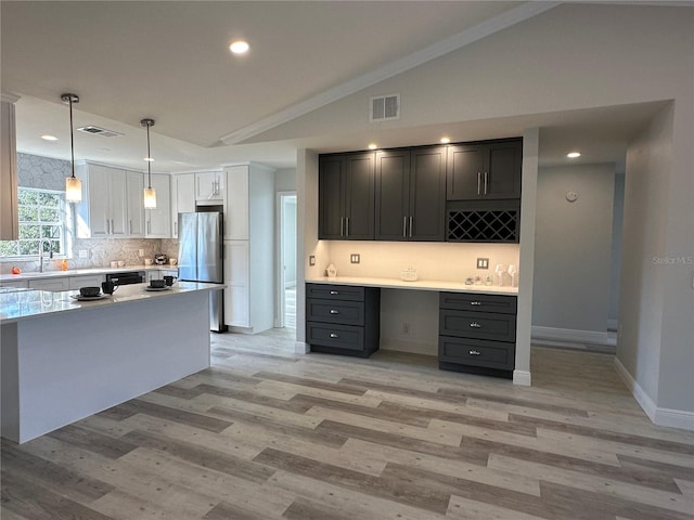 kitchen with light hardwood / wood-style floors, lofted ceiling, stainless steel fridge, and built in desk