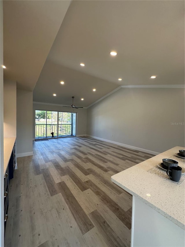 unfurnished living room featuring crown molding, vaulted ceiling, light wood-type flooring, and ceiling fan