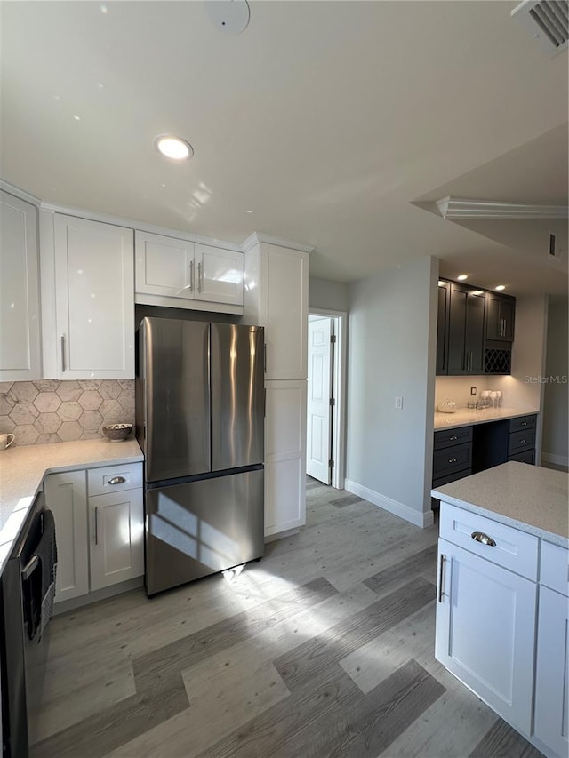 kitchen featuring appliances with stainless steel finishes, light hardwood / wood-style flooring, white cabinetry, and tasteful backsplash