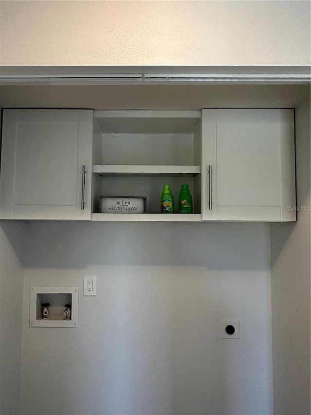 clothes washing area with hookup for a washing machine, electric dryer hookup, and cabinets