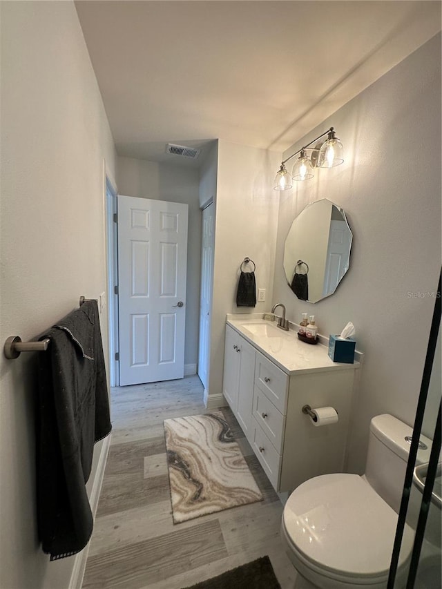 bathroom with vanity, toilet, and hardwood / wood-style floors