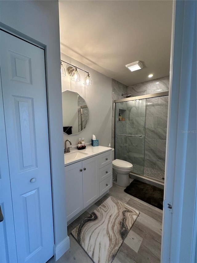 bathroom with vanity, an enclosed shower, hardwood / wood-style floors, and toilet