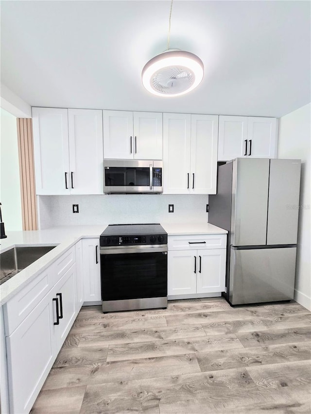 kitchen featuring sink, white cabinets, stainless steel appliances, and light wood-type flooring