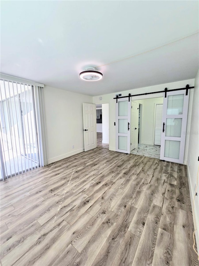 unfurnished room with light hardwood / wood-style flooring and a barn door