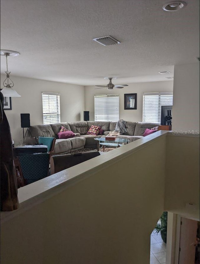 tiled living room featuring ceiling fan and a textured ceiling