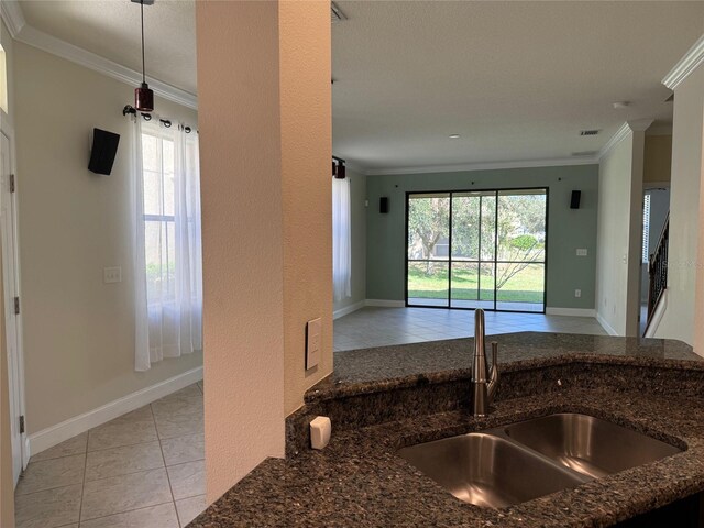 kitchen featuring crown molding, plenty of natural light, sink, and dark stone counters