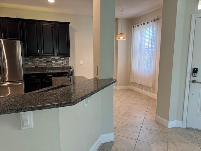 kitchen with stainless steel refrigerator, tasteful backsplash, sink, a breakfast bar area, and dark stone counters