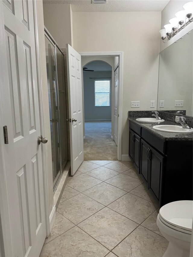 bathroom featuring vanity, toilet, a shower with shower door, and tile patterned flooring