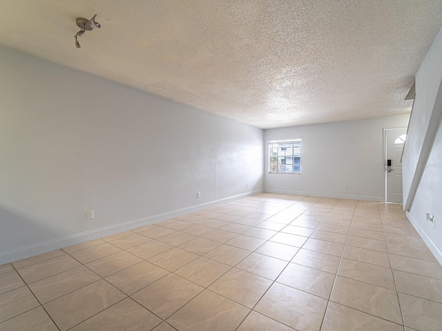 spare room featuring a textured ceiling and light tile patterned floors