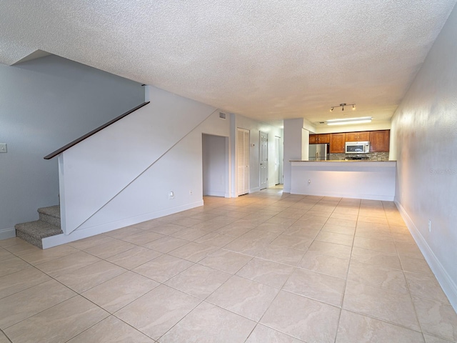 unfurnished living room with light tile patterned floors, a textured ceiling, and rail lighting