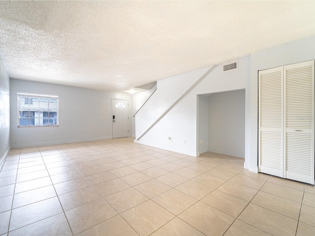 tiled spare room featuring a textured ceiling