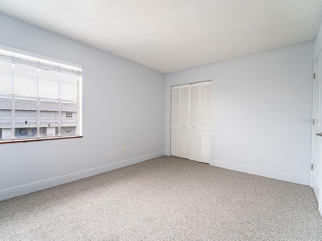 unfurnished bedroom with a textured ceiling, carpet floors, and a closet