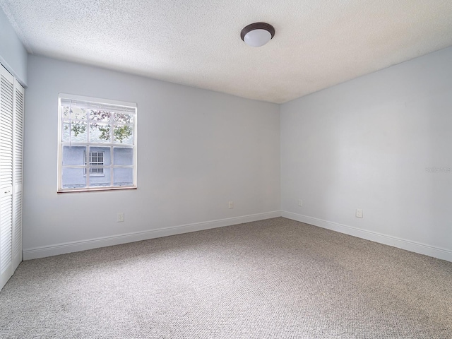 unfurnished room with carpet flooring and a textured ceiling