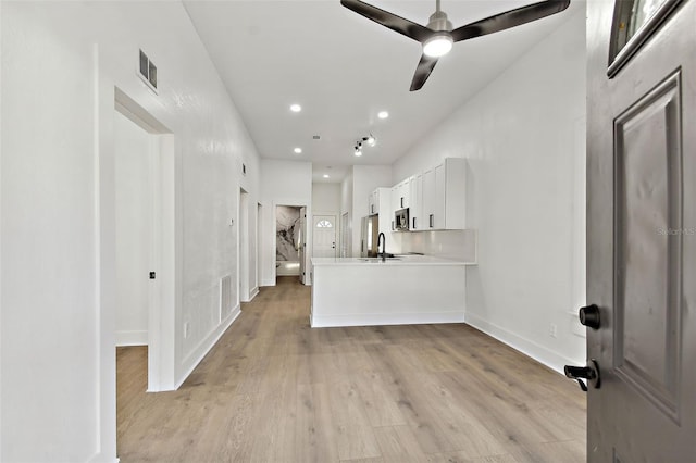 kitchen featuring kitchen peninsula, sink, white cabinets, light hardwood / wood-style floors, and ceiling fan