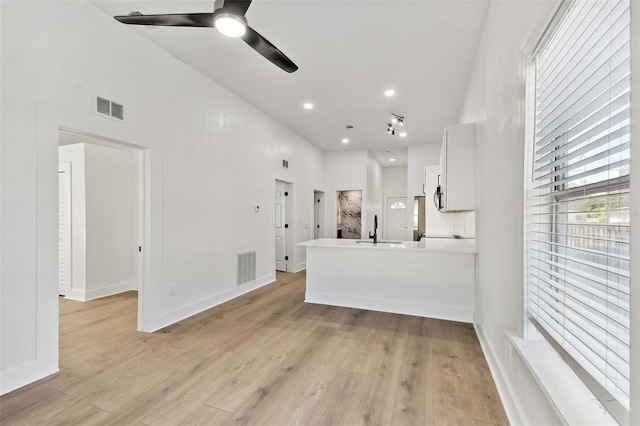 kitchen featuring sink, kitchen peninsula, ceiling fan, light hardwood / wood-style floors, and white cabinets