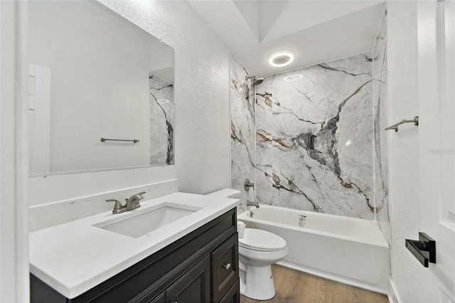 full bathroom featuring tiled shower / bath, vanity, wood-type flooring, and toilet