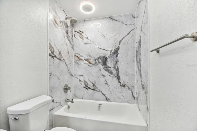 bathroom with toilet and tiled shower / bath