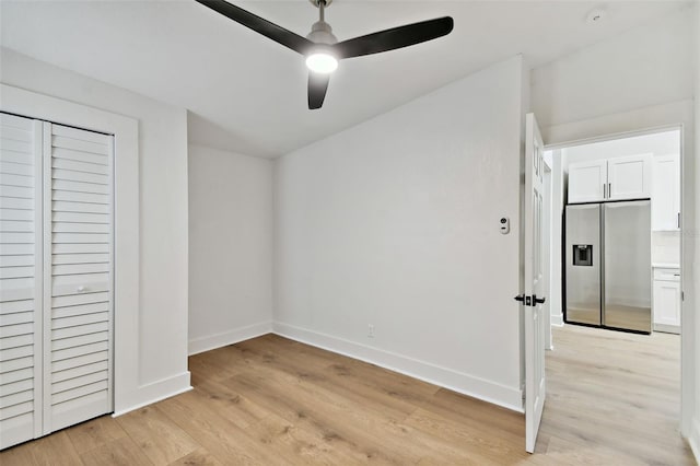 unfurnished bedroom featuring a closet, ceiling fan, stainless steel fridge with ice dispenser, and light hardwood / wood-style floors