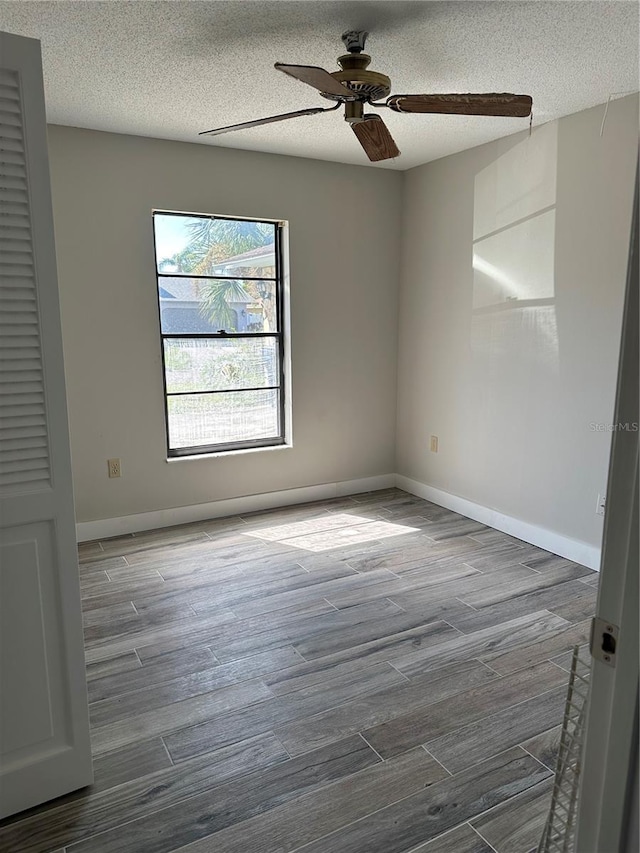 empty room featuring a textured ceiling, wood-type flooring, and ceiling fan