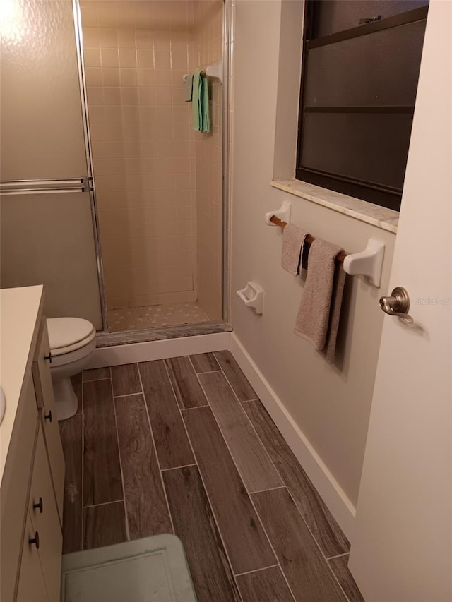 bathroom with a shower with door, vanity, and toilet